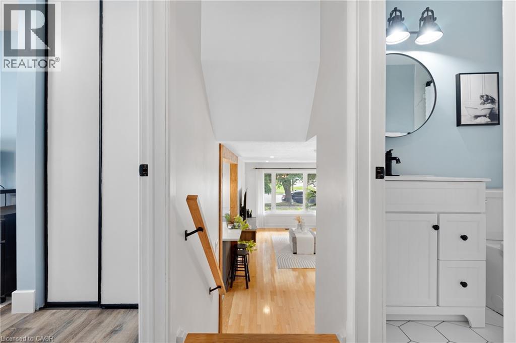 Hardwood flooring, painted white cabinetry, matte black hardware, hexagonal floor tiling, and a circular mirror - 477 Kingscourt Drive Unit# B, Waterloo, ON