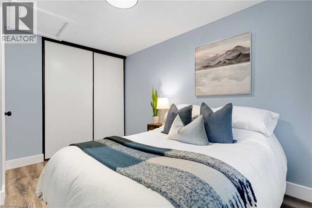 Room featuring wood-finish flooring, a flush-mount ceiling light, and a built-in closet with sliding doors - 477 Kingscourt Drive Unit# B, Waterloo, ON