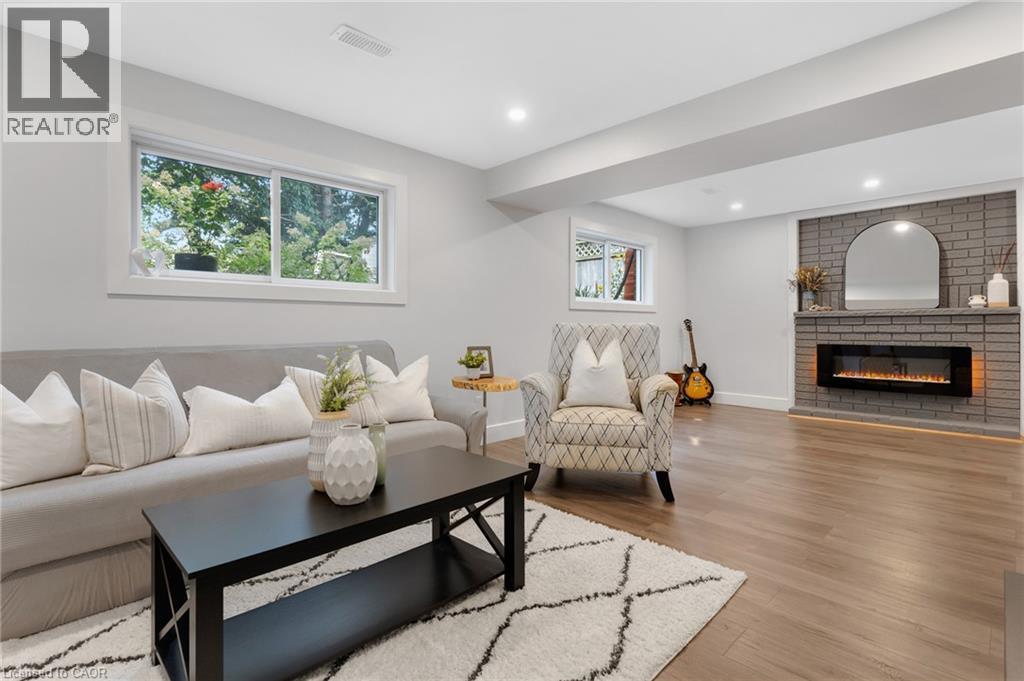 Wood-finish flooring, recessed lighting, and a grey brick fireplace with an electric insert - 477 Kingscourt Drive Unit# B, Waterloo, ON
