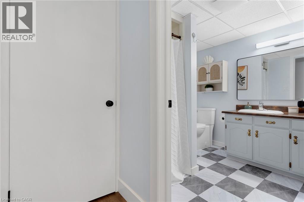Bathroom featuring a vanity with a white basin and wood-finish countertop, checkered floor tiling, and a drop-ceiling - 477 Kingscourt Drive Unit# B, Waterloo, ON