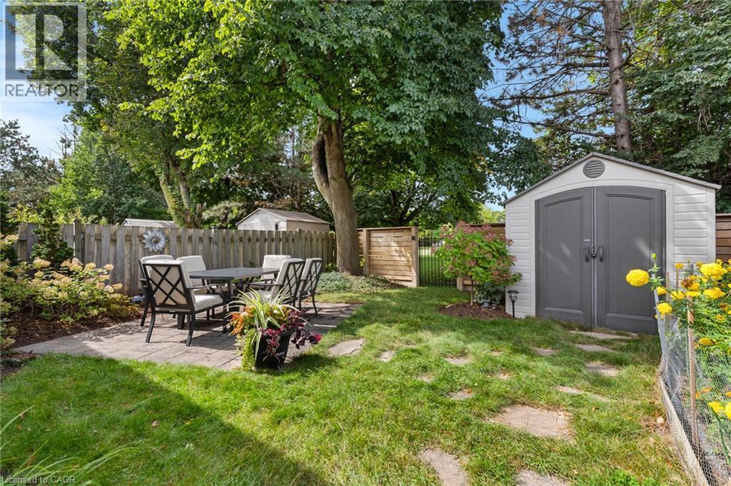 Manicured lawn with mature trees, a paved patio area, a privacy fence, and a storage shed - 477 Kingscourt Drive Unit# B, Waterloo, ON