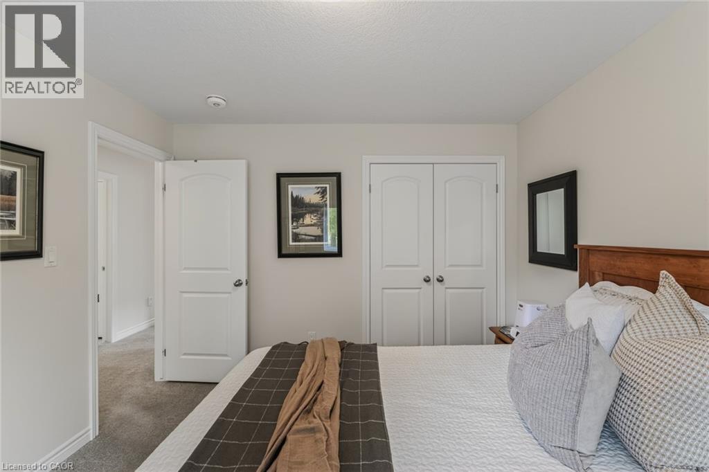 Bedroom featuring light neutral wall paint, gray carpet flooring, white trim, and a double-door closet with arch-top panels and brushed nickel hardware - 249 Woodway Trail, Simcoe, ON