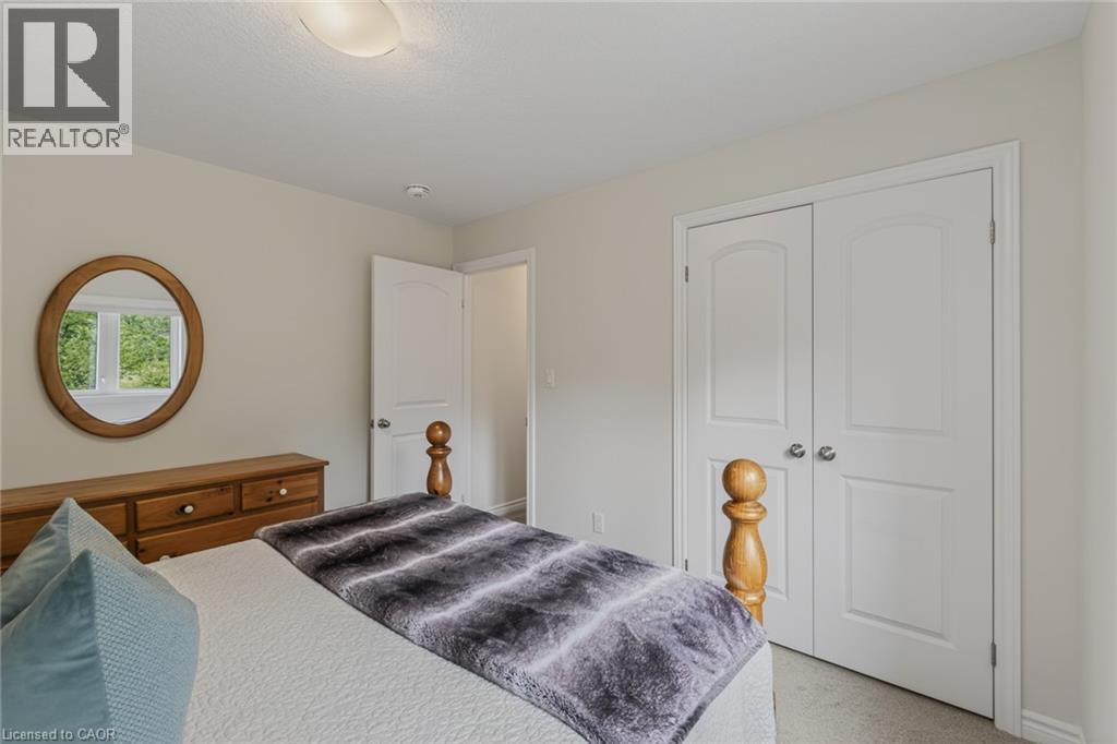 Bedroom featuring light-colored walls, carpet flooring, a ceiling-mounted light fixture, and a built-in closet with double white doors - 249 Woodway Trail, Simcoe, ON