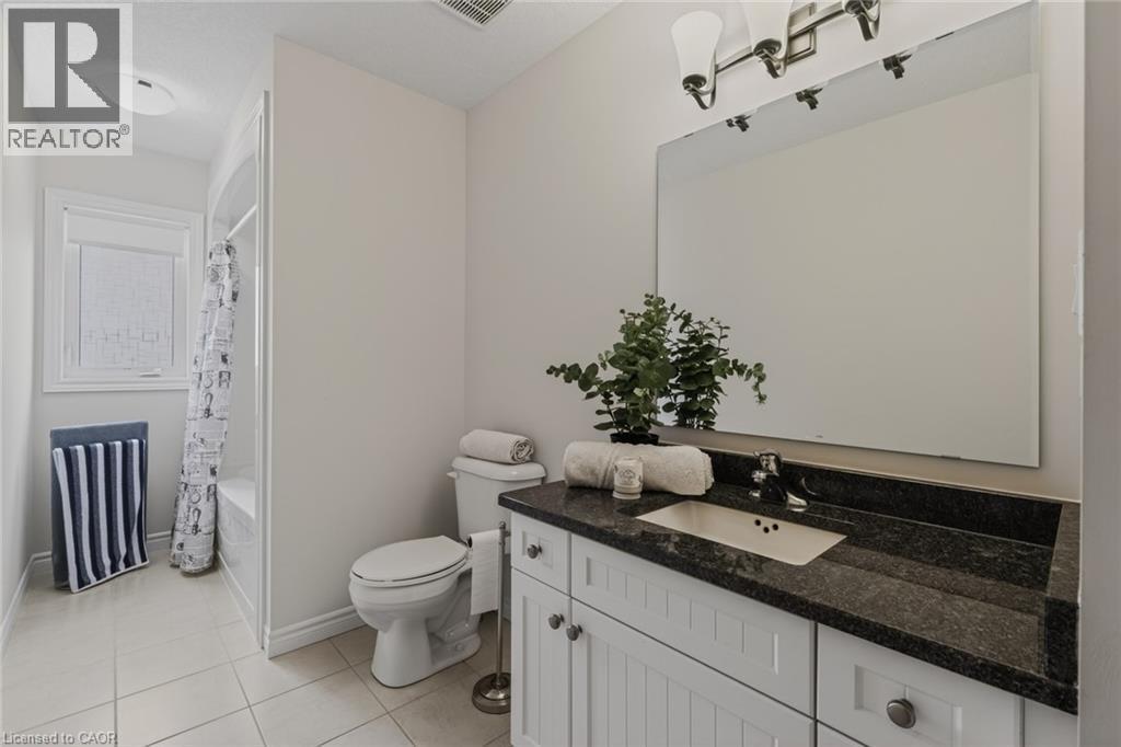 Bathroom featuring a white vanity with dark countertop, undermount sink, and large wall-mounted mirror - 249 Woodway Trail, Simcoe, ON