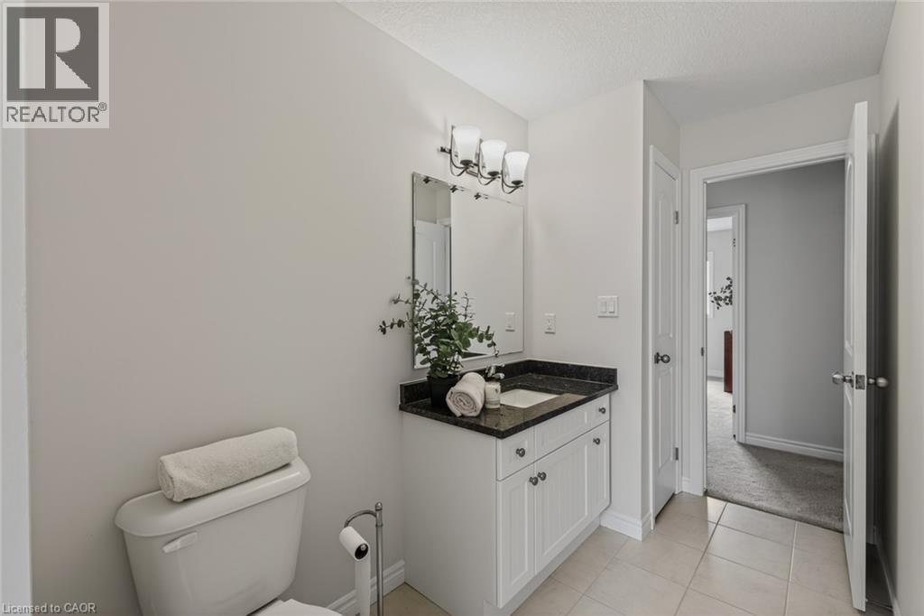 Bathroom vanity with a dark countertop and white cabinetry - 249 Woodway Trail, Simcoe, ON