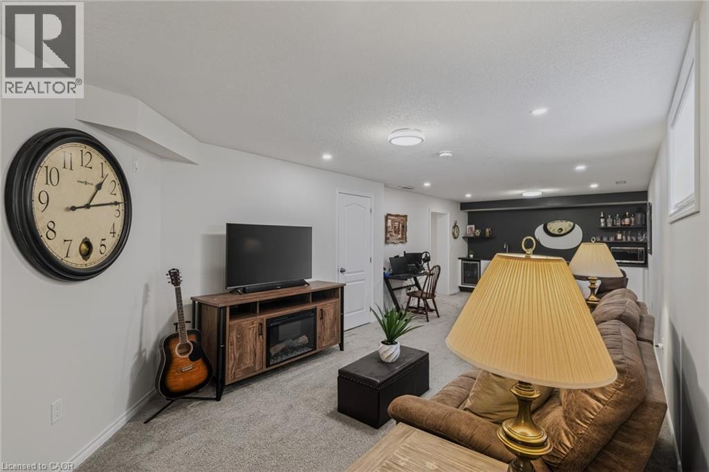 Finished lower level featuring recessed lighting, carpeted flooring, and a built-in media console with an electric fireplace - 249 Woodway Trail, Simcoe, ON