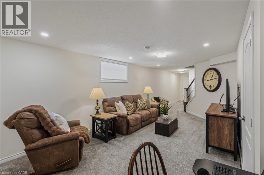 Spacious recreation room featuring light gray carpet, recessed lighting, and a white trim window - 249 Woodway Trail, Simcoe, ON