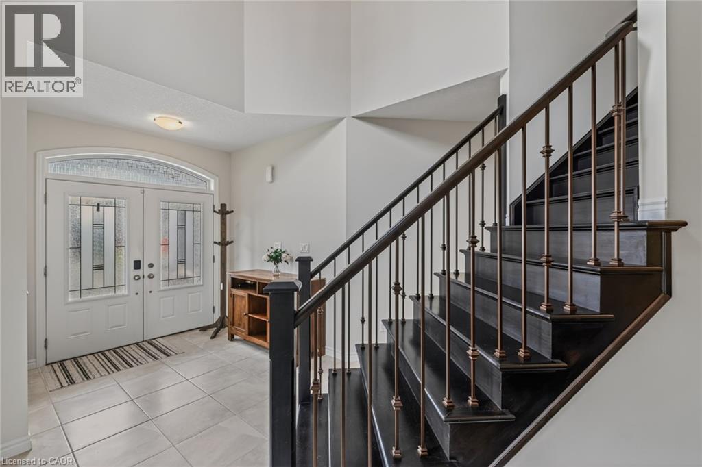 Entry foyer featuring a dark wood staircase with ornate metal balusters - 249 Woodway Trail, Simcoe, ON