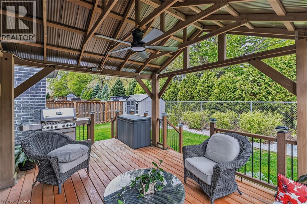 Covered wood-finish deck featuring a corrugated metal roof, exposed wood beams, and an outdoor ceiling fan - 249 Woodway Trail, Simcoe, ON