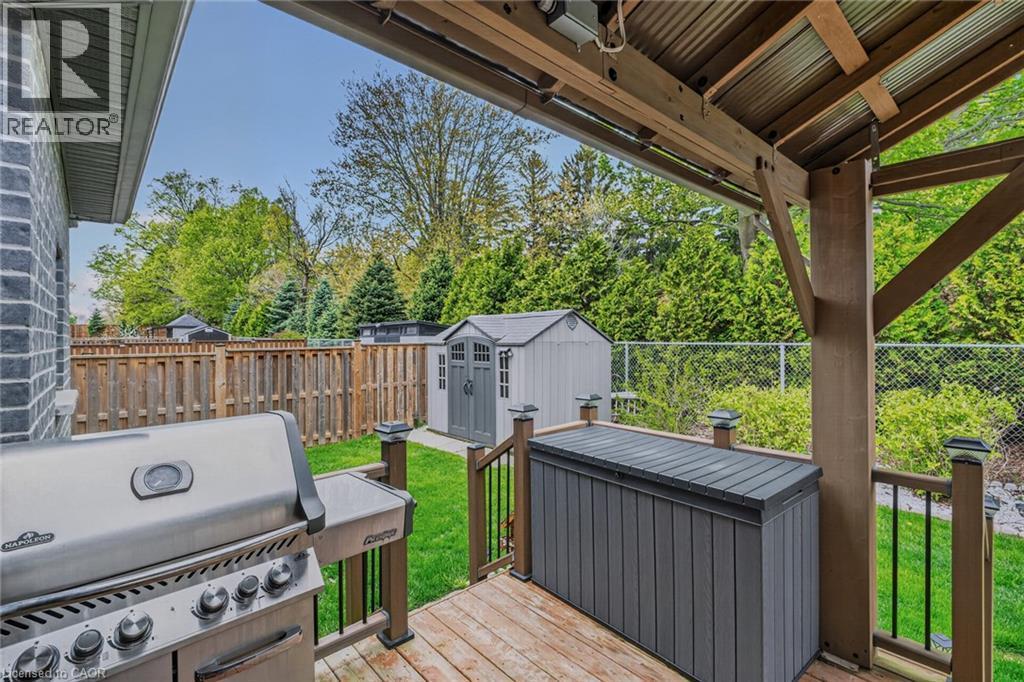Covered wood-finish deck with a corrugated metal ceiling and a privacy screen - 249 Woodway Trail, Simcoe, ON