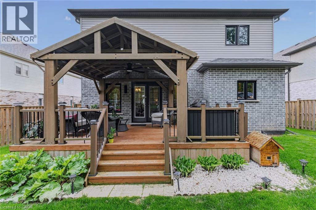 Expansive wooden deck featuring a covered gazebo with a ceiling fan, black metal railings, and direct access to the interior via double French doors - 249 Woodway Trail, Simcoe, ON