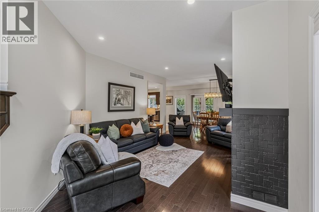 Open concept living space featuring recessed lighting, dark wood-finish flooring, a textured black accent wall, and white wall finishes - 249 Woodway Trail, Simcoe, ON