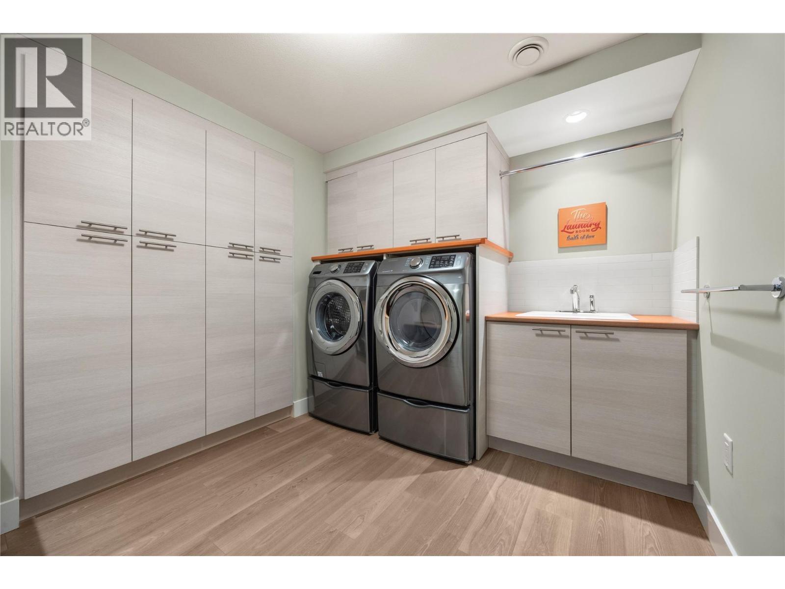 Lower level Laundry room with built in cabinetry, front loading washer and dryer and sink - 2442 Bella Vista Street, Kelowna, BC