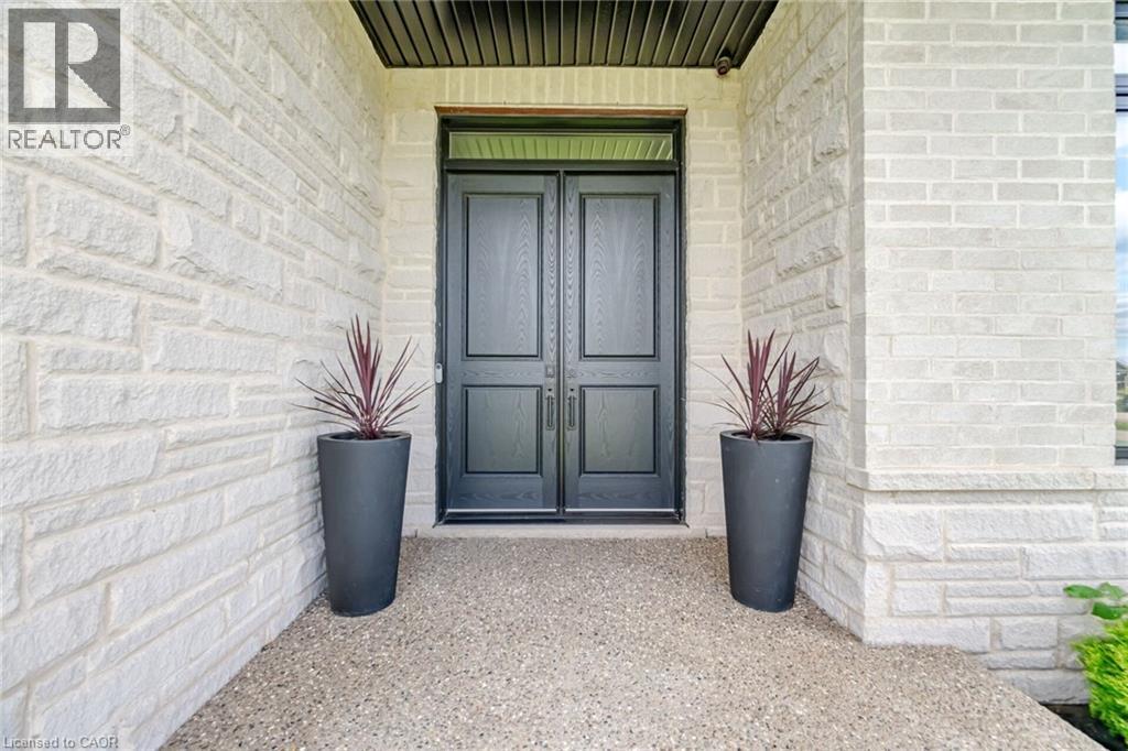 White stone exterior with black double entry doors and a textured concrete walkway - 56 Augustus Street, Scotland, ON