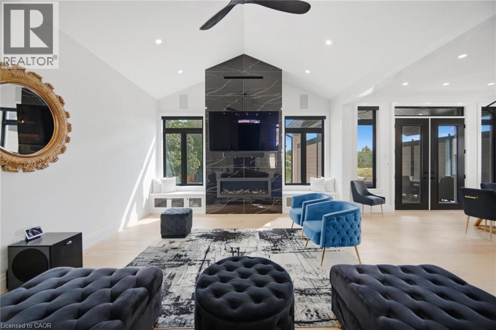 Vaulted ceiling, recessed lighting, black fireplace with integrated television, window seating, and light wood-finish flooring - 56 Augustus Street, Scotland, ON
