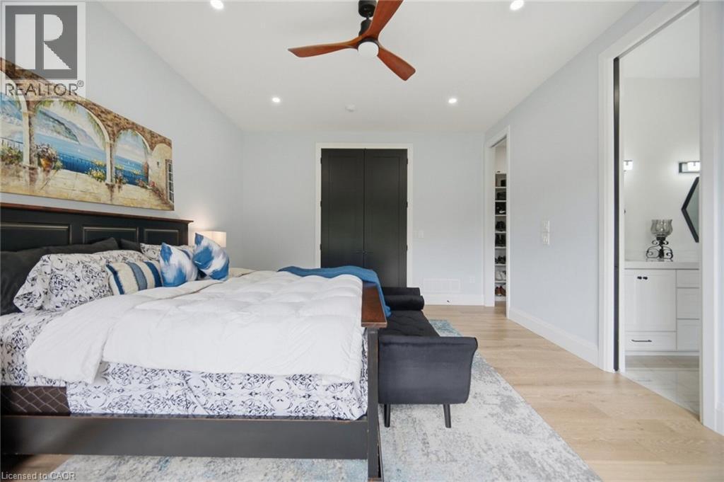 Recessed lighting, wood-finish flooring, ceiling fan, dark panel door, and white vanity with a mirror - 56 Augustus Street, Scotland, ON