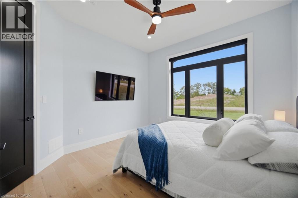 Natural wood-finish flooring, a contemporary ceiling fan, and a large multi-pane window with a roller shade - 56 Augustus Street, Scotland, ON
