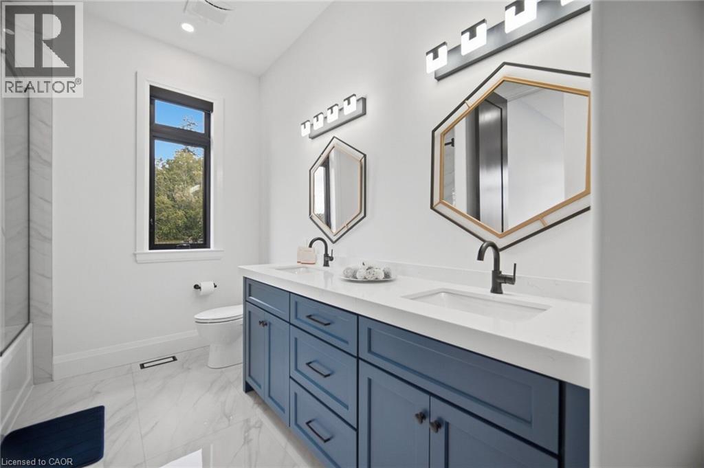 Dual vanity with blue cabinetry, white countertop, undermount sinks, and matte black fixtures - 56 Augustus Street, Scotland, ON
