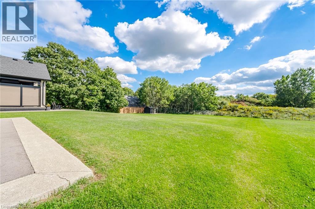 Expansive green lawn with mature trees and a concrete walkway - 56 Augustus Street, Scotland, ON