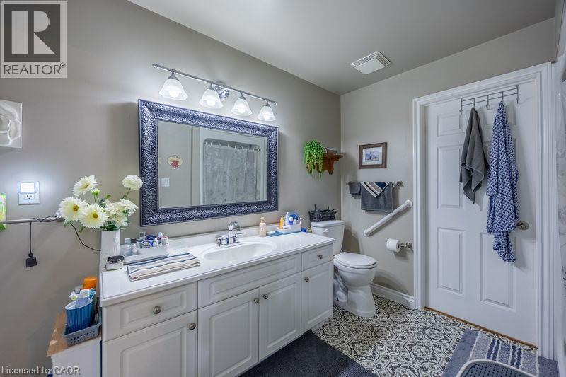 White vanity with a single basin sink, framed mirror, and decorative tile flooring - 123 Mill Street, Delhi, ON