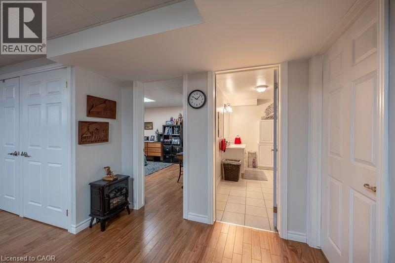 Wood-finish flooring throughout, white paneled doors, and a tiled bathroom with a vanity and mirror - 123 Mill Street, Delhi, ON