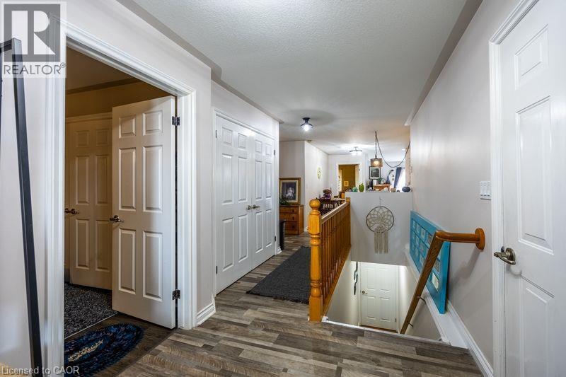 Wood-finish flooring throughout, white paneled doors, and a wood banister with balusters - 123 Mill Street, Delhi, ON