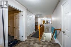 Wood-finish flooring throughout, white paneled doors, and a wood banister with balusters -