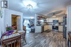 Kitchen featuring light-finish cabinetry, stainless steel appliances, open shelving, and wood-finish flooring -