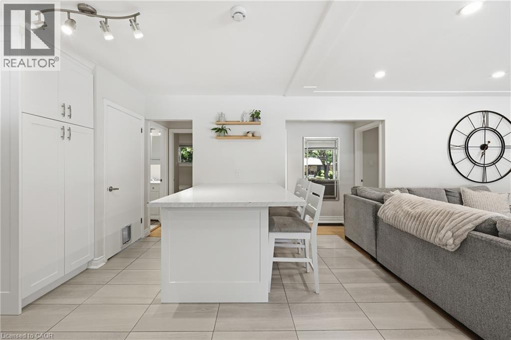 White shaker-style cabinetry with silver hardware, recessed lighting, track lighting, light-toned tile flooring, and a stone-finish island countertop - 312 Upper Paradise Road, Hamilton, ON