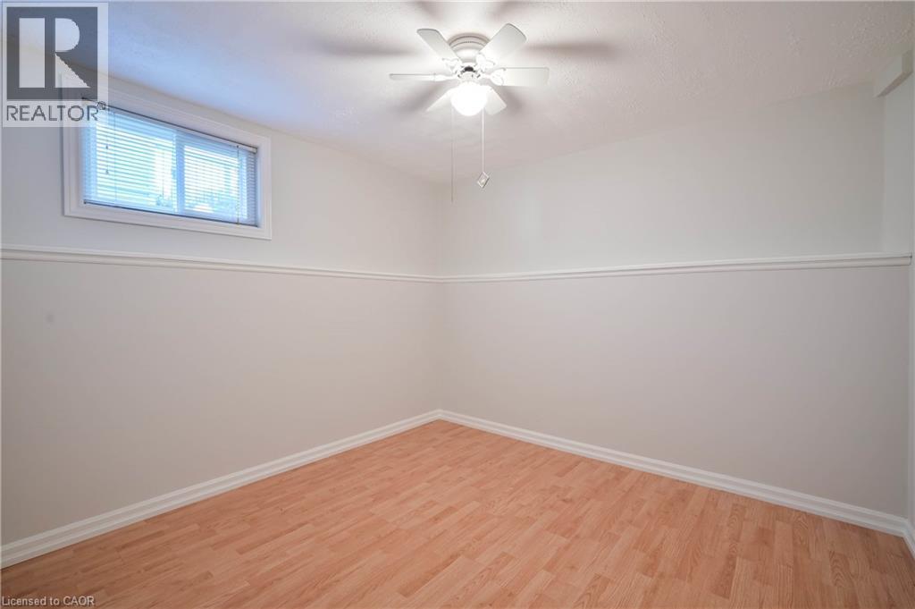 Wood-finish flooring, white walls with chair rail molding, ceiling fan with integrated lighting, and a white-framed window with blinds - 12 Langevin Drive, Wasaga Beach, ON