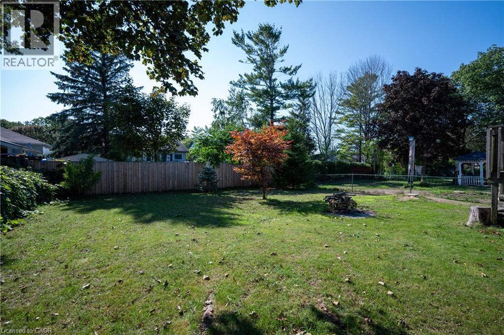 Expansive grassy yard with a privacy fence, mature trees, and a wooden gazebo - 12 Langevin Drive, Wasaga Beach, ON