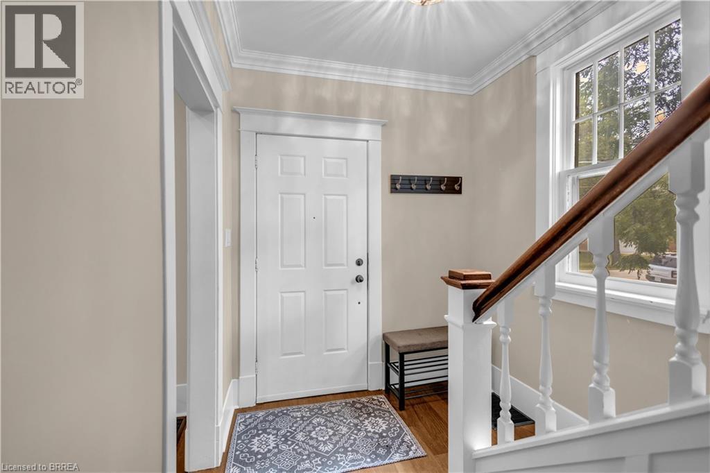 Panel door entry with crown molding, wood-finish flooring, and a traditional staircase featuring a wood handrail - 11 Tutela Heights Road, Brantford, ON