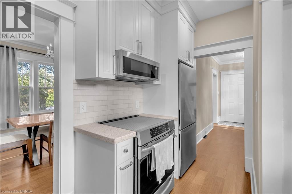 Stainless steel appliances, white shaker cabinetry, light wood-finish flooring, subway tile backsplash, and a light-toned countertop - 11 Tutela Heights Road, Brantford, ON