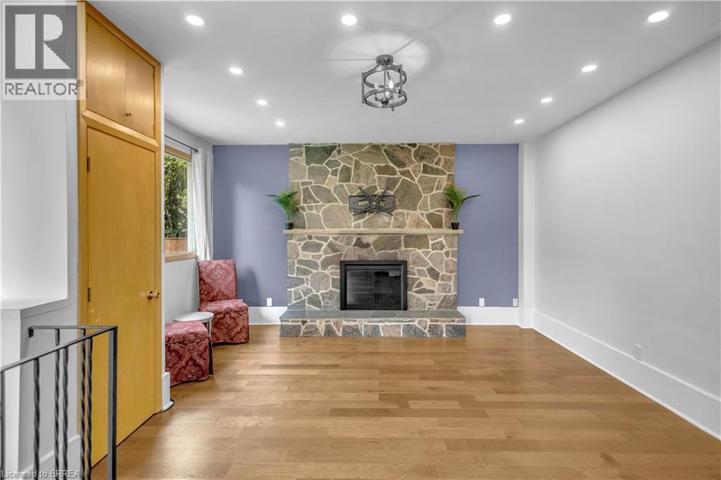 Hardwood flooring, recessed lighting, stone fireplace, modern chandelier, and built-in cabinetry - 11 Tutela Heights Road, Brantford, ON