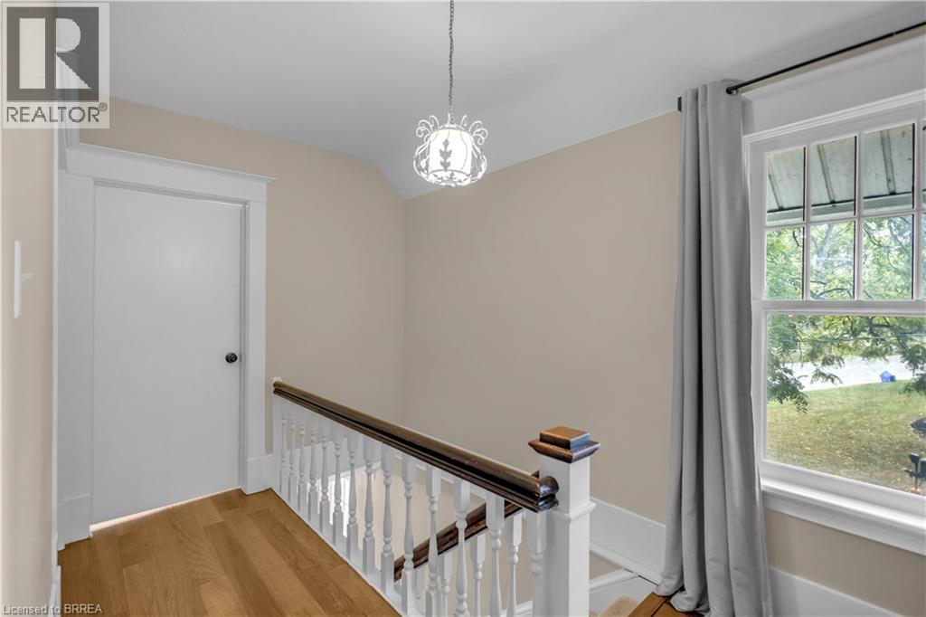 Hardwood-finish flooring, white spindle banister with wood-finish railing, single-hung window, and decorative ceiling light fixture - 11 Tutela Heights Road, Brantford, ON