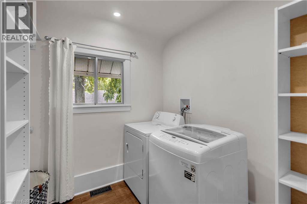 Laundry area featuring wood-finish flooring, built-in shelving, and a window with white trim - 11 Tutela Heights Road, Brantford, ON