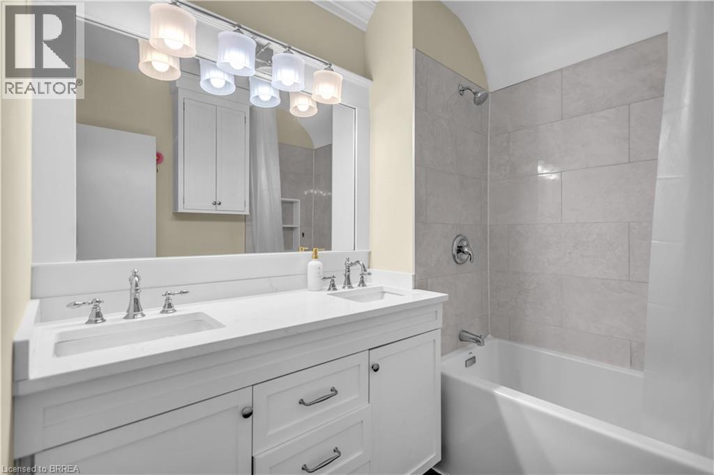 Dual sink vanity with white cabinetry, polished chrome fixtures, and a large mirror - 11 Tutela Heights Road, Brantford, ON