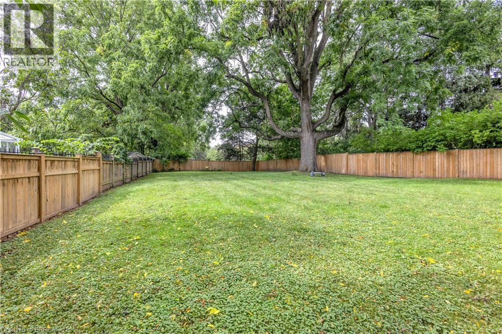 Expansive green lawn with mature trees and wood fencing - 11 Tutela Heights Road, Brantford, ON