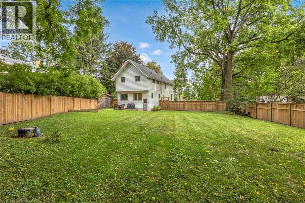 Expansive backyard featuring a manicured lawn, full wood fencing, and mature trees - 11 Tutela Heights Road, Brantford, ON