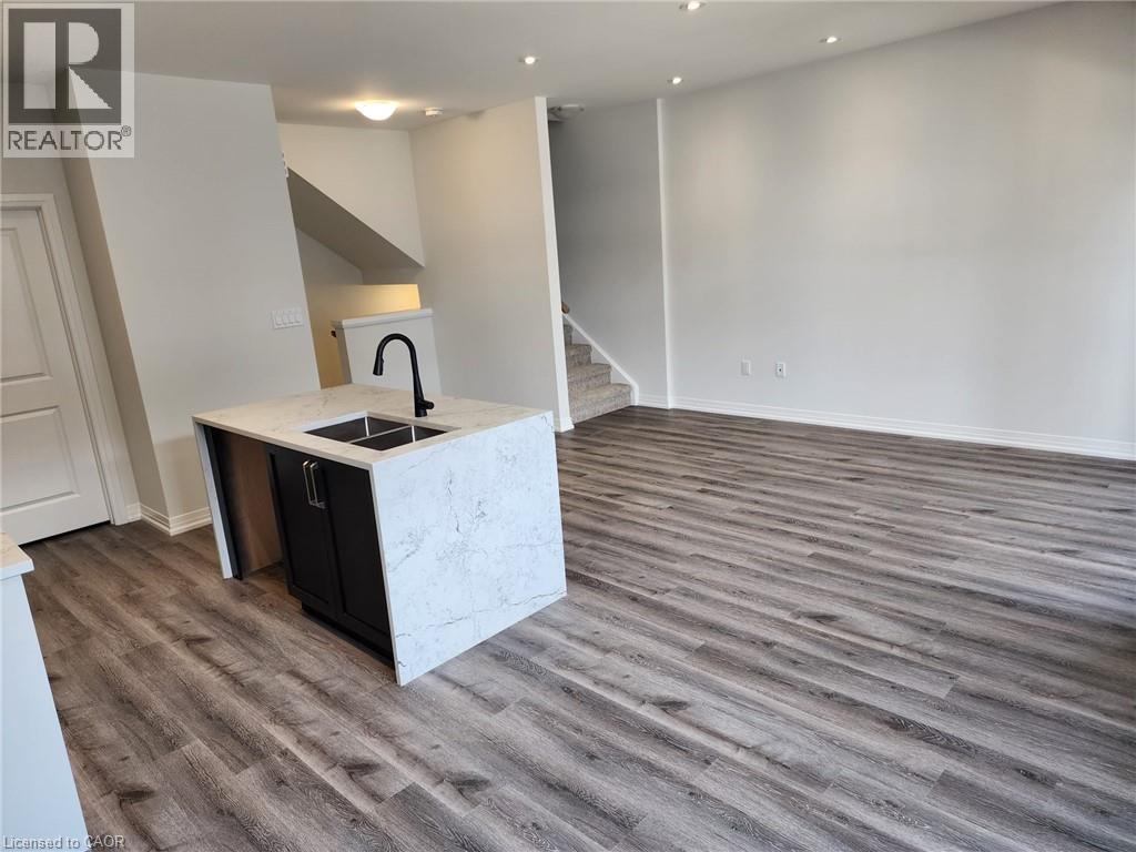 Kitchen island with stone countertop, undermount sink, and matte black faucet - 155 Equestrian Way Unit# 152, Cambridge, ON