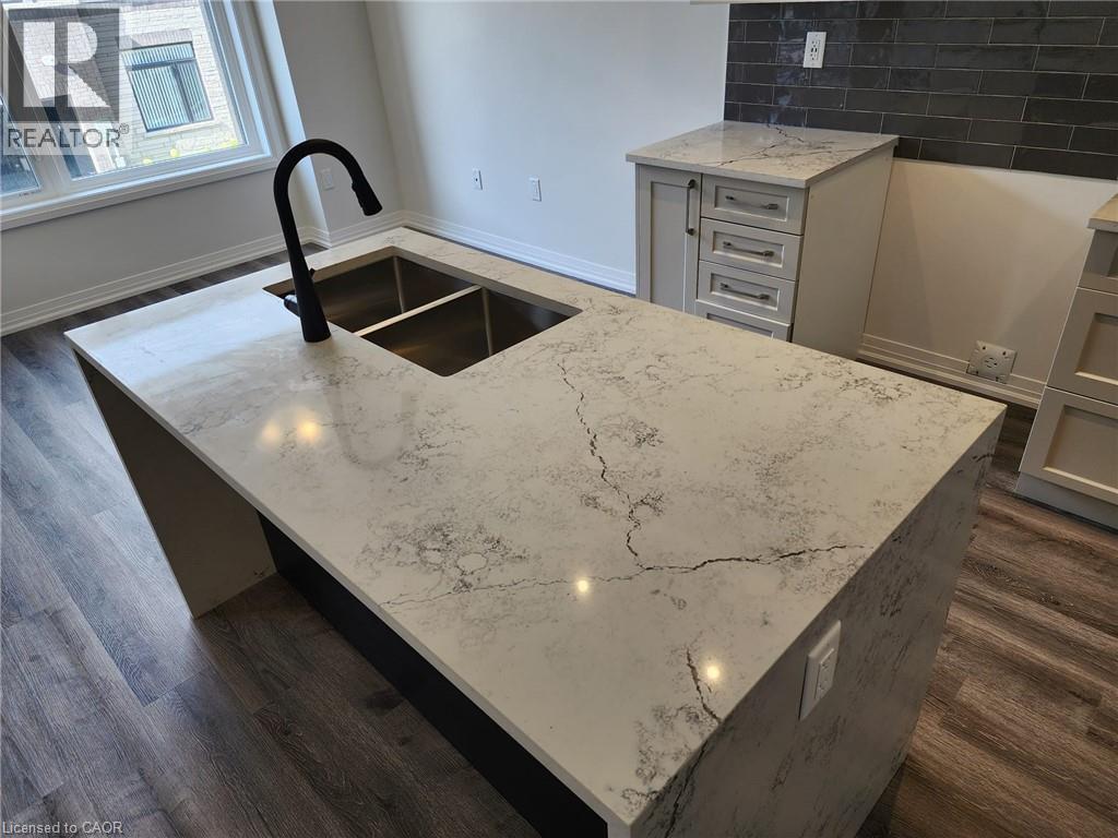 Kitchen island with a dual stainless steel sink, matte black faucet, and patterned stone countertop - 155 Equestrian Way Unit# 152, Cambridge, ON