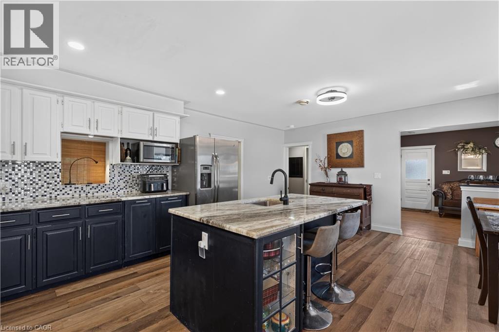 Kitchen featuring a central island with stone countertop, integrated sink, and seating - 42841 Highway 3, Wainfleet, ON