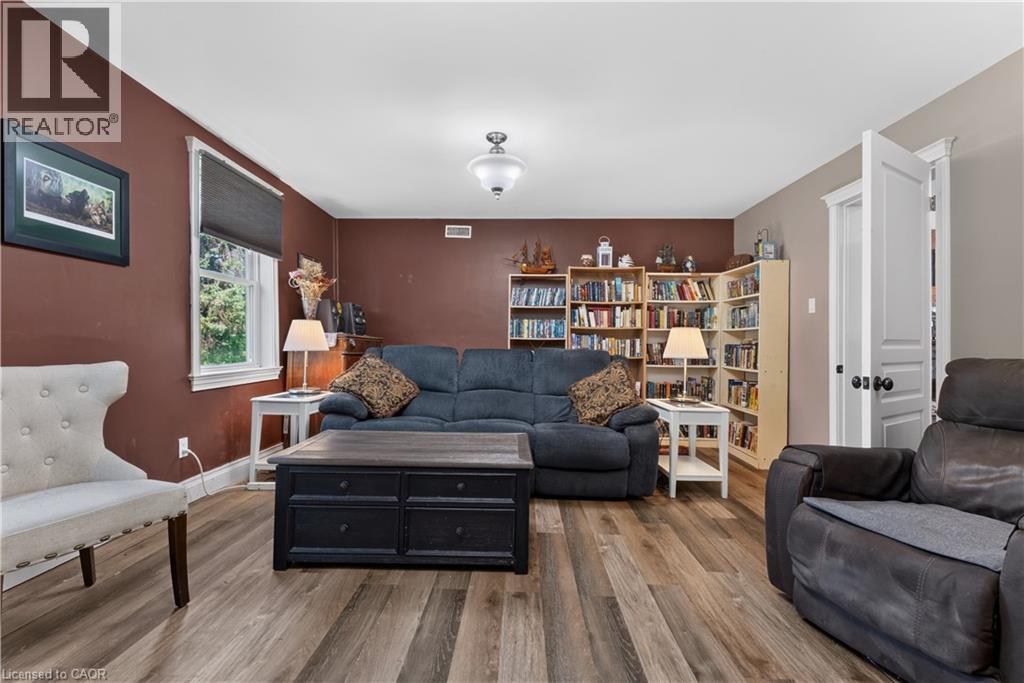 Spacious room featuring wood-finish flooring, a ceiling-mounted light fixture, and a window with white trim - 42841 Highway 3, Wainfleet, ON