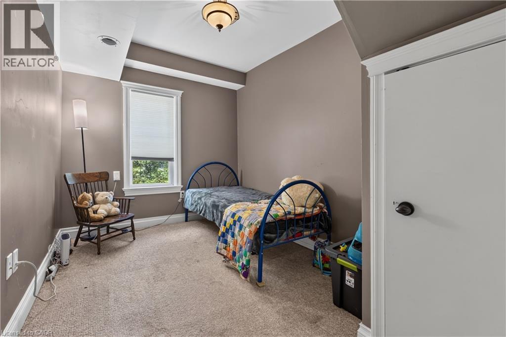 Carpeted room featuring a single window with blinds, a ceiling-mounted light fixture, crown molding, and a white interior door with black hardware - 42841 Highway 3, Wainfleet, ON
