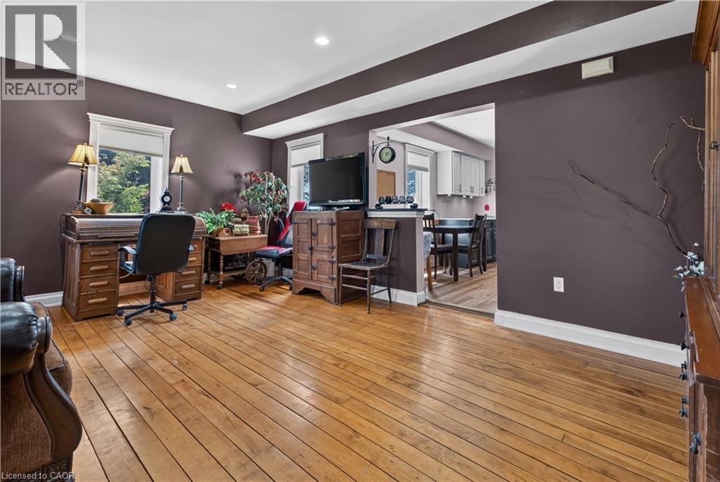 Hardwood flooring and recessed lighting define this interior space, featuring a wide doorway opening to a dining area with white cabinetry - 42841 Highway 3, Wainfleet, ON