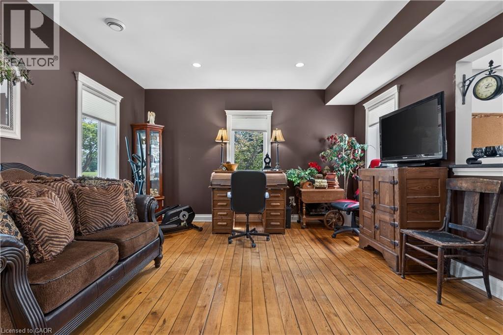Spacious room with wood-finish flooring, multiple windows with white trim, recessed ceiling lighting, and dark-toned walls - 42841 Highway 3, Wainfleet, ON