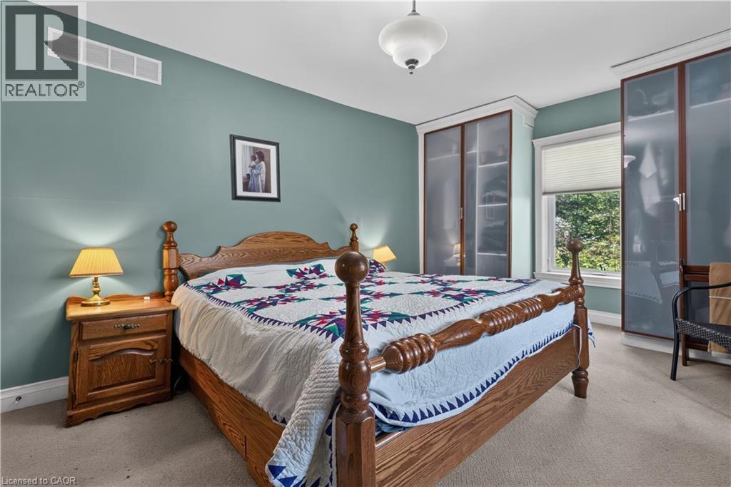 Bedroom featuring built-in cabinetry with frosted glass doors, a single window with blinds, and light carpet flooring - 42841 Highway 3, Wainfleet, ON