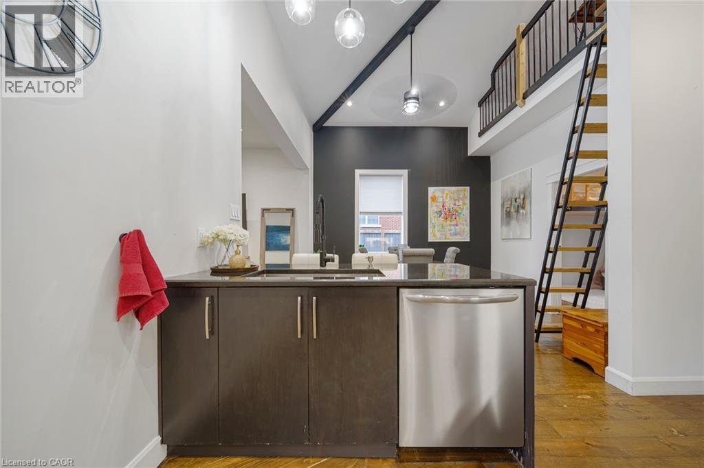 Kitchen island with dark wood-finish cabinetry, stainless steel dishwasher, and a dark countertop - 28 Cambridge Street, Cambridge, ON