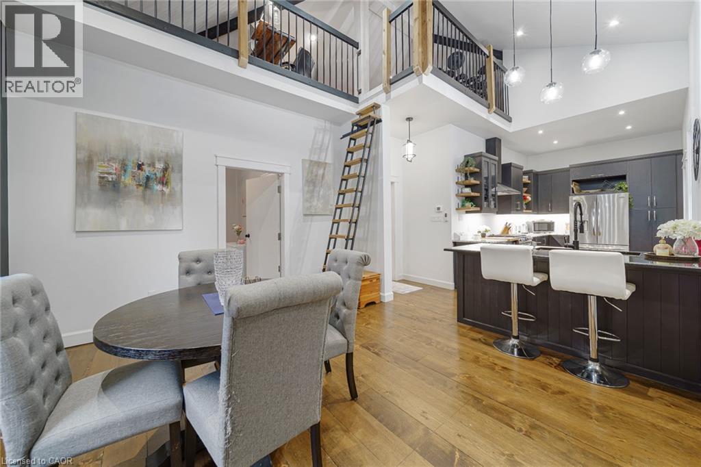 Vaulted ceilings, wood-finish flooring, a built-in kitchen island, stainless steel appliances, and an overhead loft with a wrought-iron railing - 28 Cambridge Street, Cambridge, ON