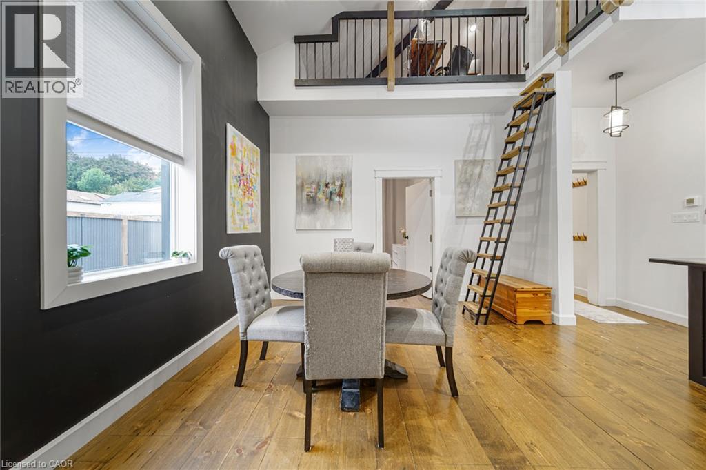 Wood-finish flooring throughout, featuring a distinctive high ceiling and a built-in loft with metal railing - 28 Cambridge Street, Cambridge, ON